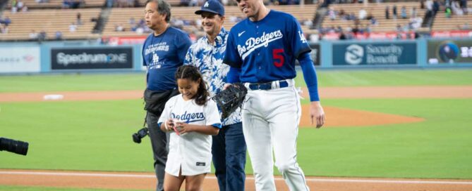 Photo of a girl representing the winning Youth Recycling Challenge team with Dodgers player and Public Works Director on field at Dodger Stadium.