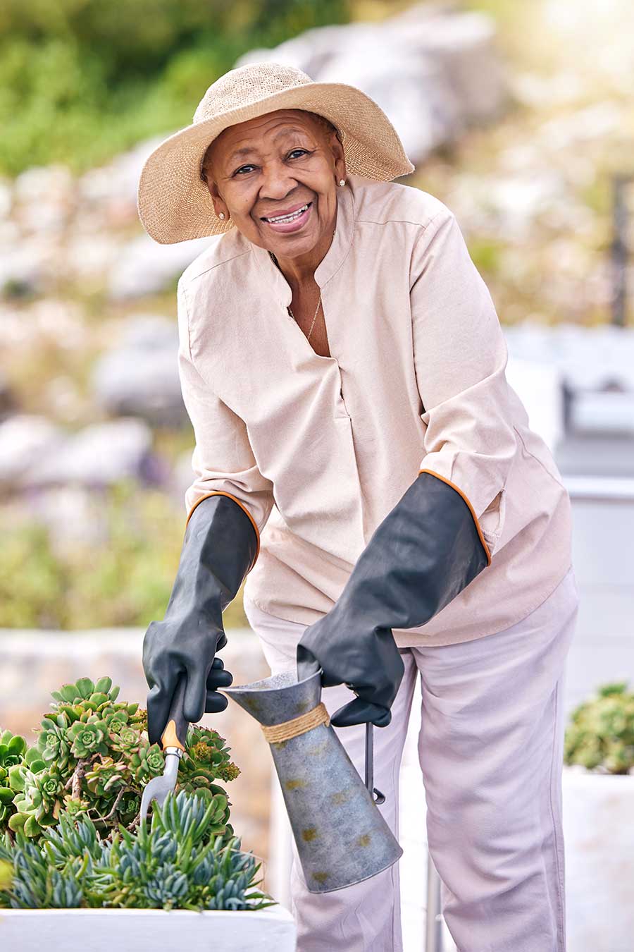 Elderly woman tending to drought tolerant garden.