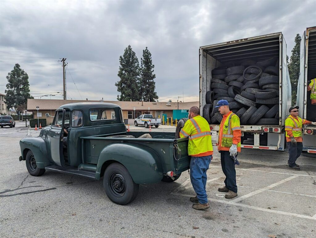 LA County Public Works staff unload used automobile tires from an antique pickup truck at a tire recycling event.